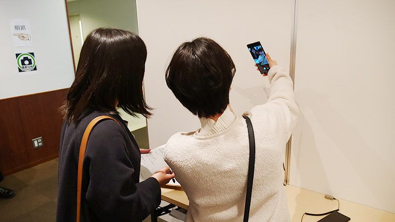 スマートフォンで自撮りを試す若い女性2名の後ろ姿