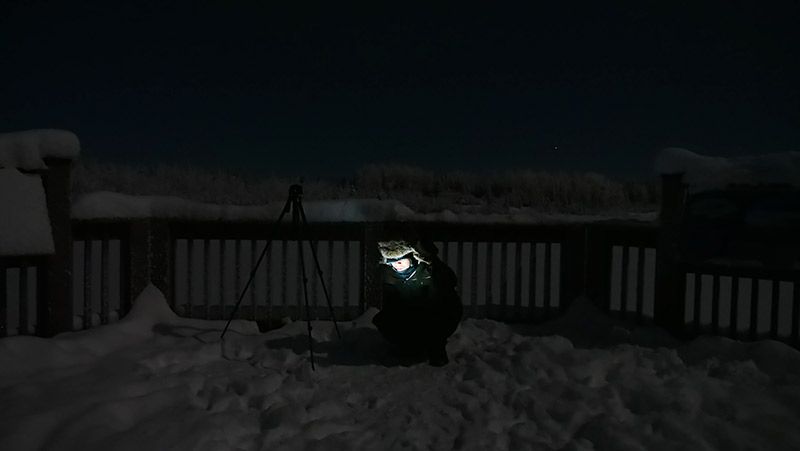 雪原の中で座りながらTORQUE G03を見る地主