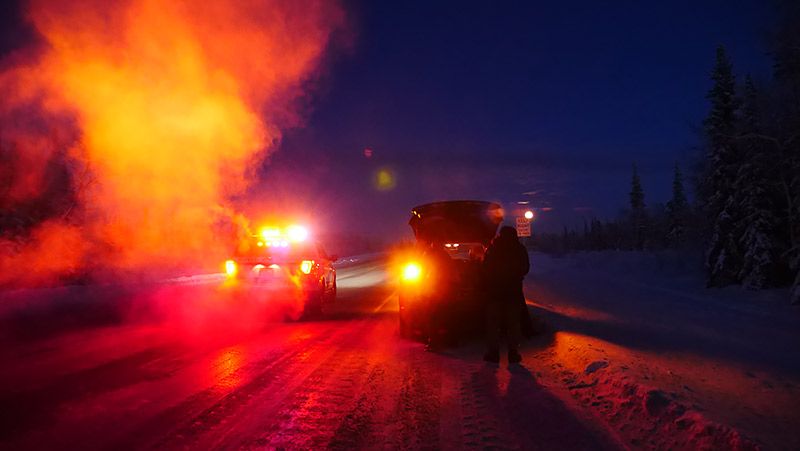 アラスカの道路で赤いランプで近づいてくる警察車両