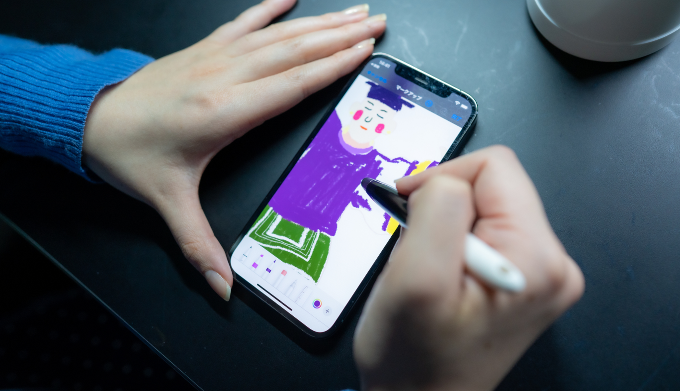 KDDIのコンセプトショップ GINZA 456 とチームラボとのコラボによる体験型イベント Walk, Walk, Walk Home においてスマホの専用アプリでぬり絵する女性