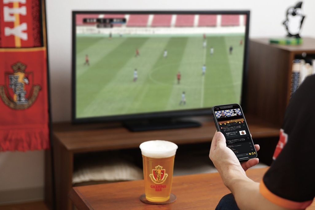 サッカーの試合を見ながら「名古屋グランパス公式アプリ」で自宅から応援する様子