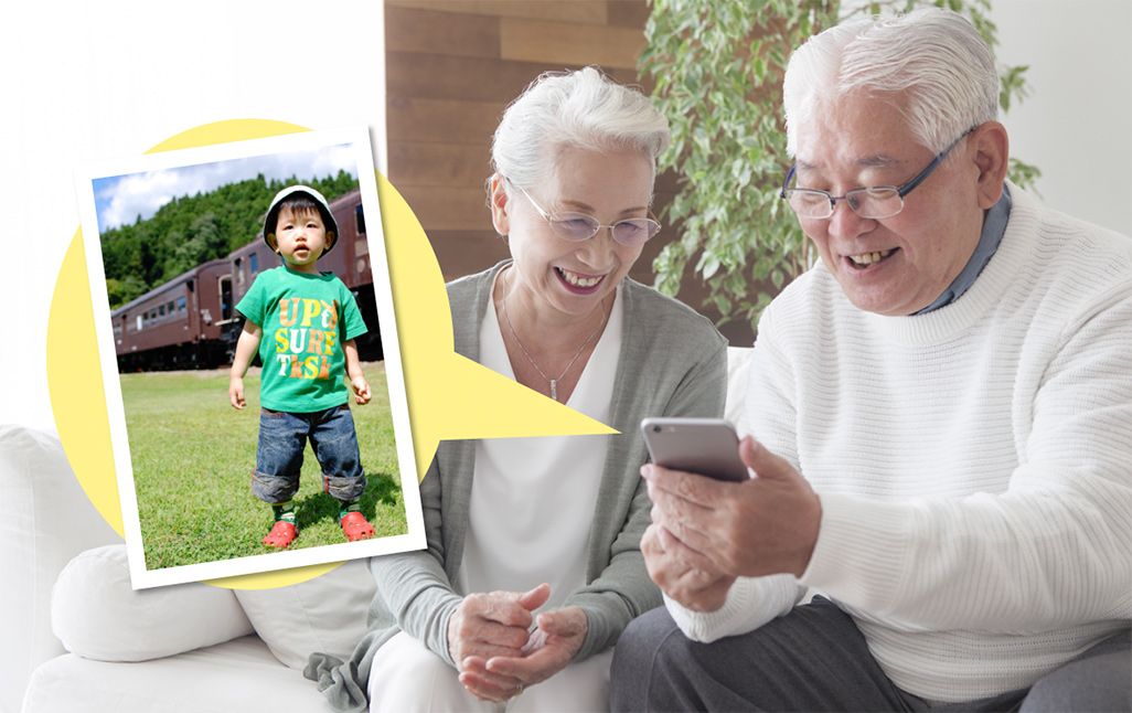 スマホで孫の写真を見る祖父母