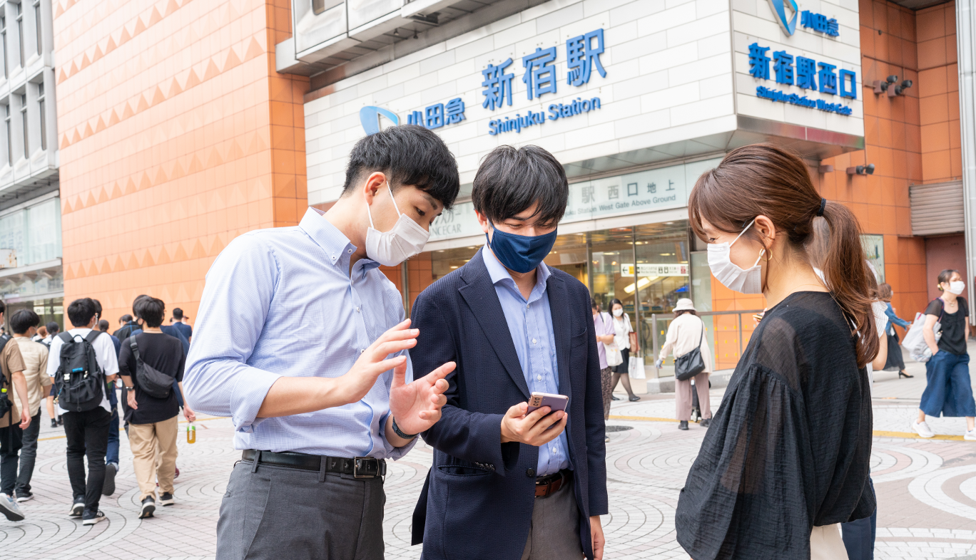 新宿駅西口でau5Gの通信エリアを調査をする人
