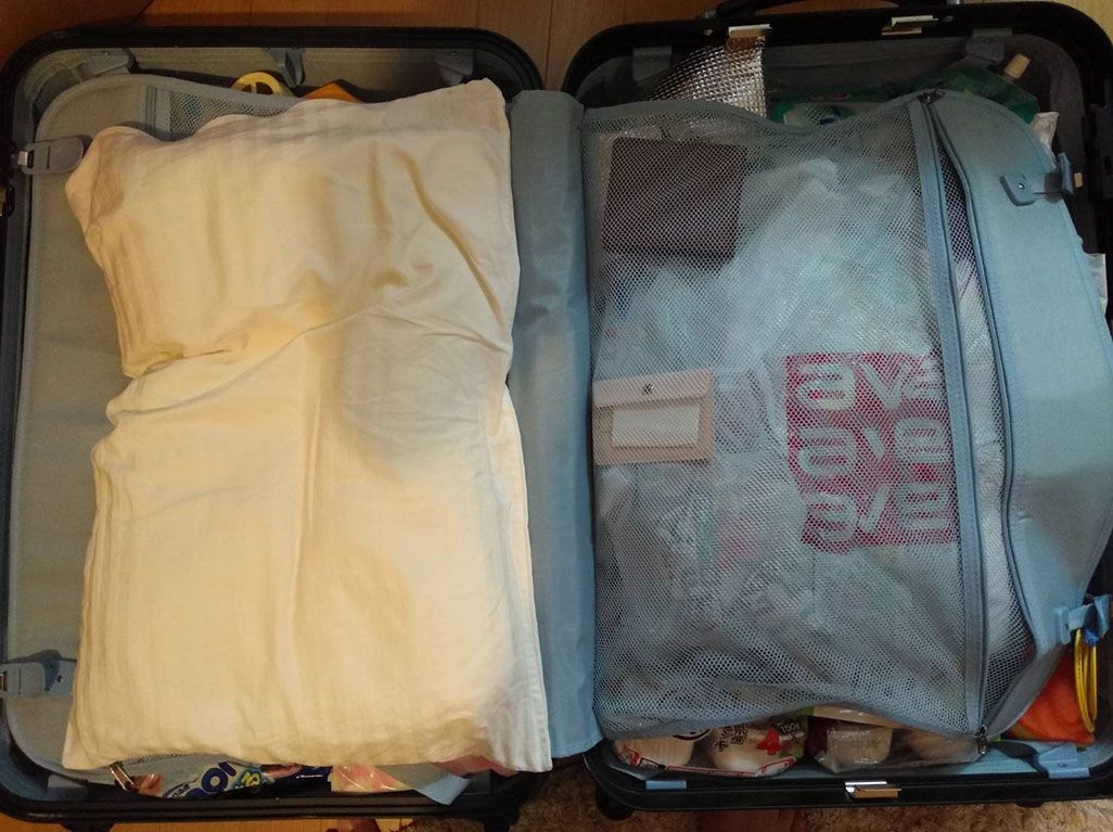 KDDI・三戸が現地に持ち込むスーツケース。マイ枕が見える