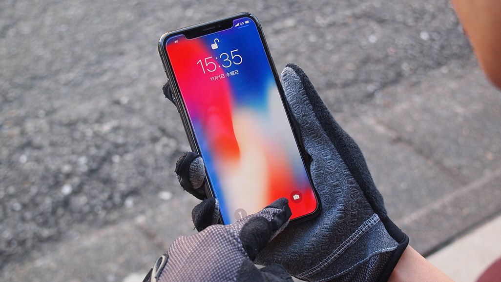 手袋をはめたまま、iPhone Xのロックを解除する男性