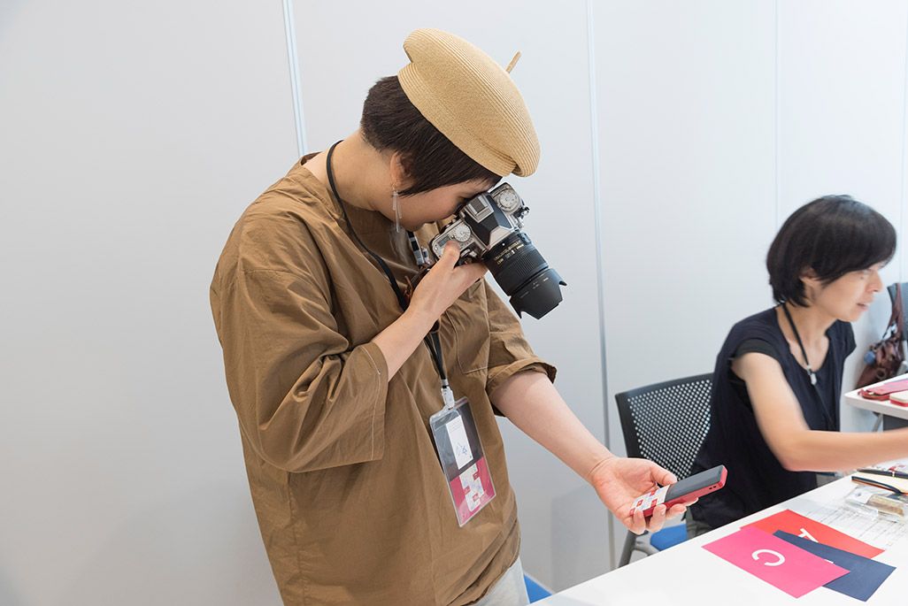 INFOBARファンミーティング新宿で披露されたINFOBAR xvのデザインモックを撮影する参加者