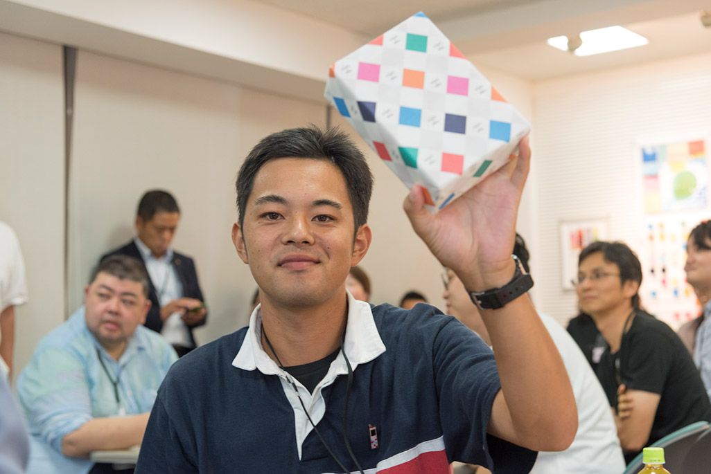 クイズ大会の優勝賞品を掲げる男性