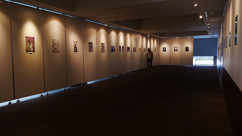 写真展の準備が完了し、光の当たらない場所に地主がぽつんといる様子
