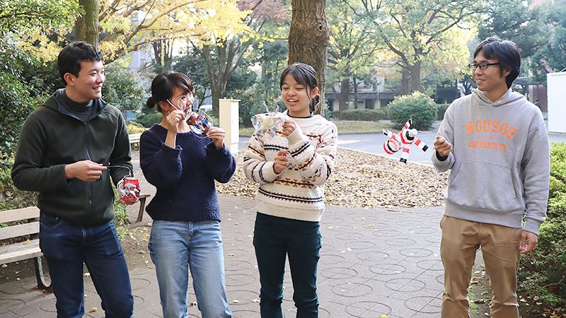 大学生と手作りの風車をもちながら談笑するライターの地主恵亮