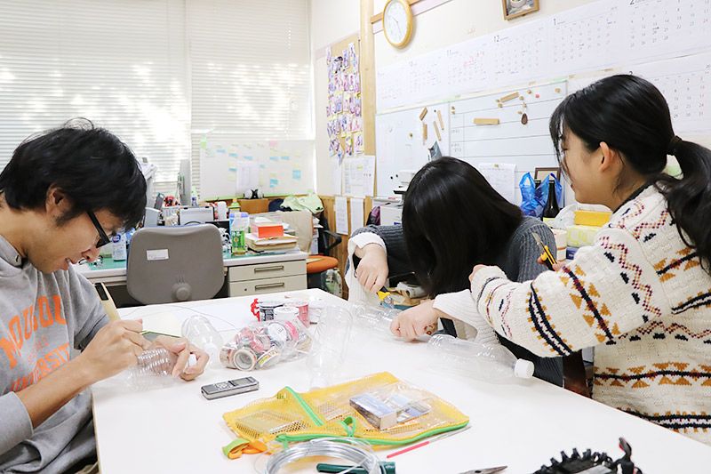 ペットボトルにカッターを入れる3名