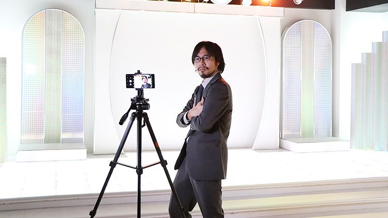 ステージの前で、腕を組みながらスマホで自撮りをする地主
