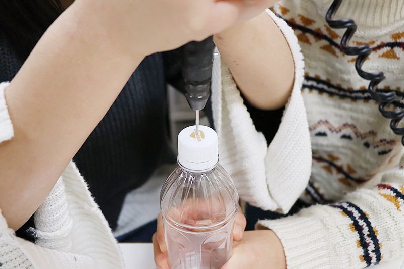 ペットボトルのフタに穴をあけている様子