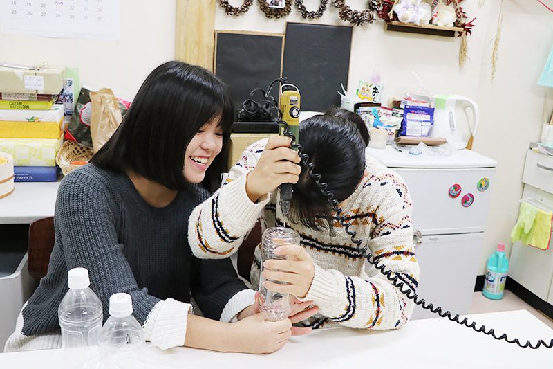 ペットボトルの底に穴をあけている大学生2名