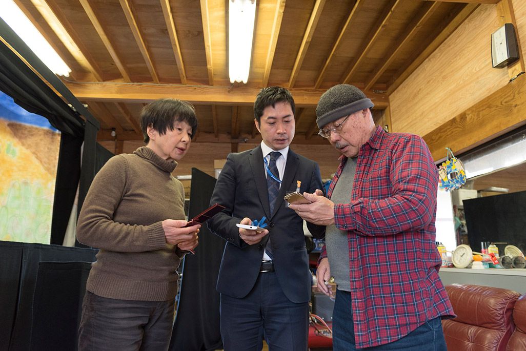 自宅内のアトリエでスマホを取り出し、電波状況を確認するサポーター