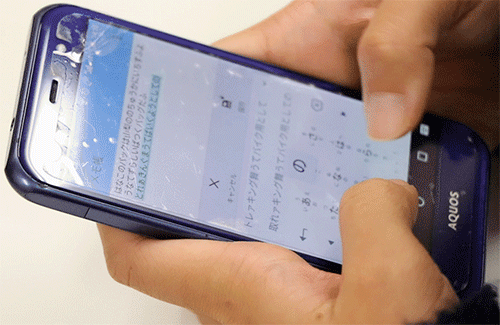 青いスマートフォンでフリック入力をしている様子