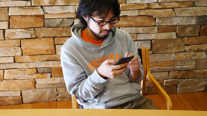 室内でスマートフォンをいじる地主