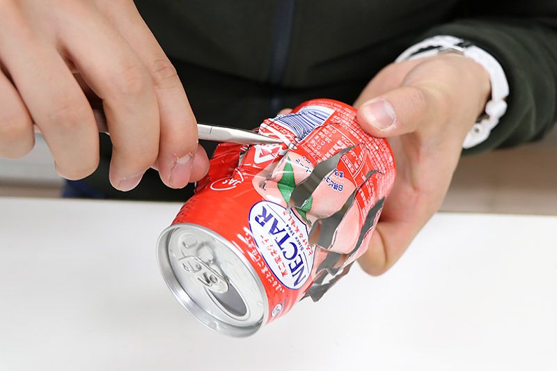 空き缶の切れ目をひねり、羽を作っている様子