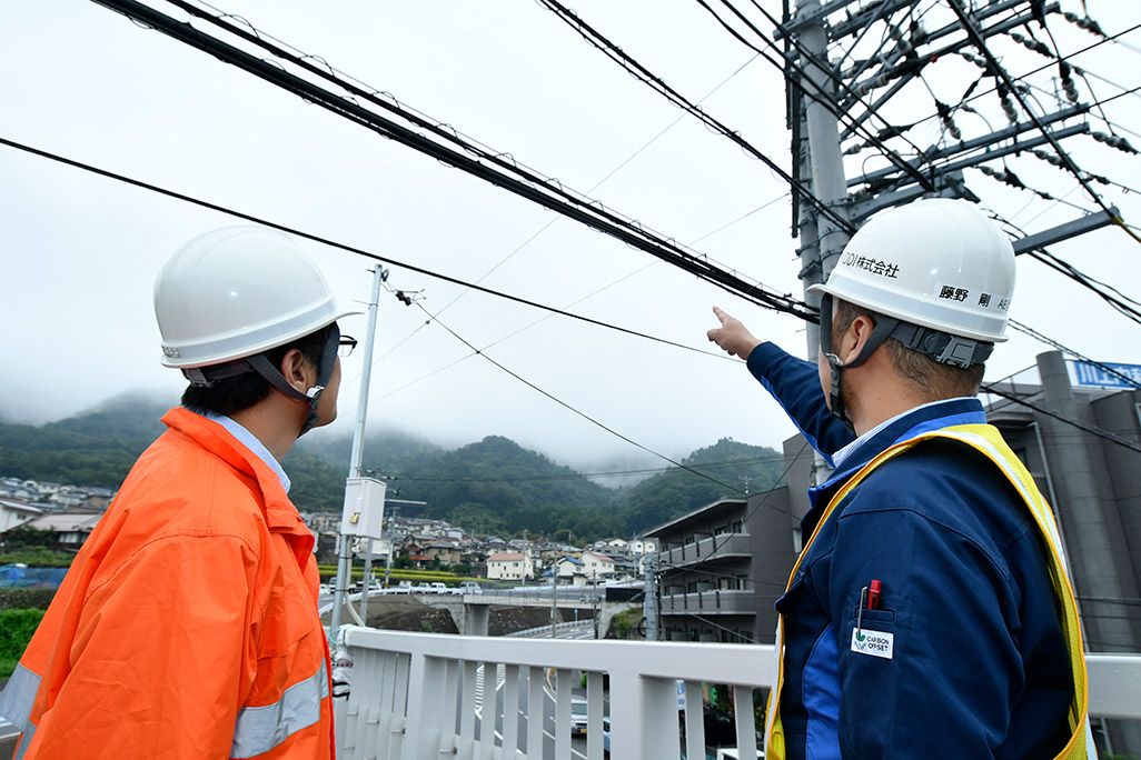 光ケーブルを電柱づたいのルートに切り替えることを検討する作業着姿の2人の男性