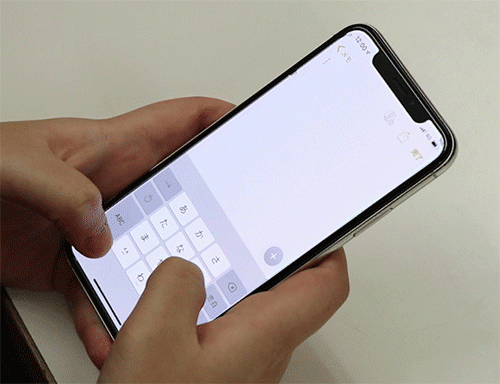 スマートフォンでフリック入力をしている様子